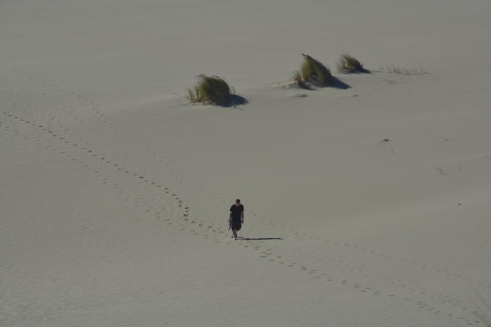 man walking sandy dunes